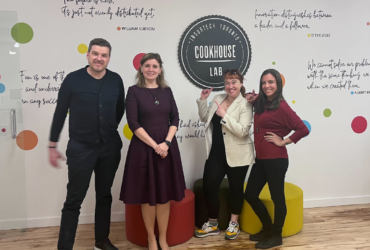 Four smiling thinktum staff standing at a photo wall, with Insurtech Toronto Cookhouse Lab logo.
